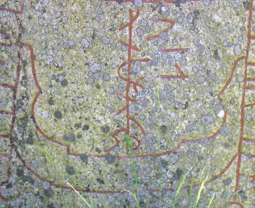 Photo of a rune stone showing a line drawing of a boat with the mast made of runes.